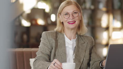 Portrait-of-Smiling-Senior-Businesswoman-with-Laptop-in-Restaurant